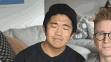 a man wearing glasses and a black beanie looks at the camera