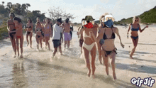 a group of people in bikinis are running in the water on a beach