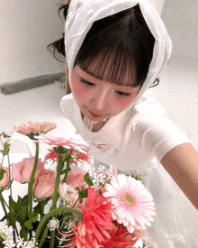 a girl wearing a white shirt with the word cherry on it looks at flowers