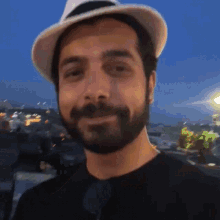 a man with a beard wearing a hat and black shirt