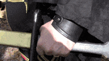 a person holding a sword with a black leather wristband