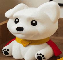 a white stuffed animal with a yellow collar and a red cape