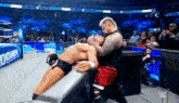 two men are wrestling in a stadium with a sign that says ' smack down ' on it
