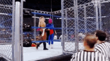 a woman in a pink mask is standing in a wrestling ring with a referee watching .