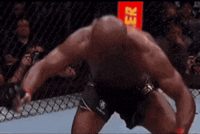 a man is kneeling down in a boxing ring with a red sign in the background that says gr