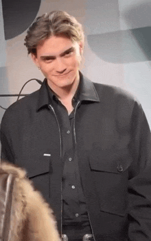 a young man wearing a black jacket and black shirt