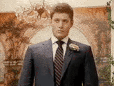 a man in a suit and tie is standing in a room with a chandelier .