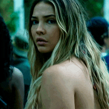 a woman without a shirt looks at the camera