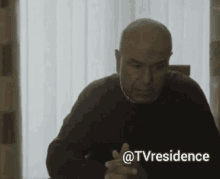 a man sitting at a table with a sticker that says @tvresidence on it