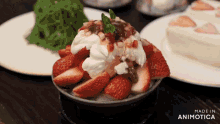 a bowl of strawberries and whipped cream on a table with a made in animatica logo