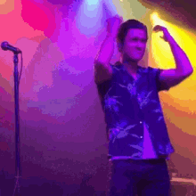 a man in a hawaiian shirt is standing in front of a microphone on a stage