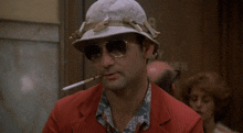 a man in a hat and sunglasses is smoking a cigarette