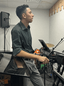 a man sits at a keyboard with a drum set behind him
