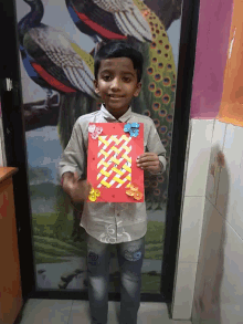 a young boy holds up a piece of paper with flowers on it in front of a peacock painting
