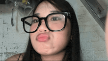 a woman wearing glasses making a funny face with her tongue out