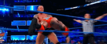 a wrestling match is being held in a ring with a referee .
