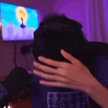 a person is covering their face with their hands in front of a television .