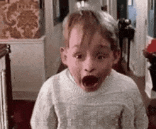 a young boy in a sweater is making a funny face .