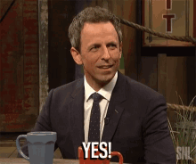 a man in a suit and tie is smiling and says yes