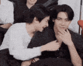 a couple of young men are sitting next to each other on a couch and laughing .