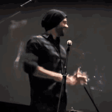 a man wearing a black beanie is speaking into a microphone