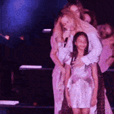 a woman is singing into a microphone while hugging a little girl on stage .