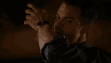 a man is wearing a watch on his wrist while standing in the dark .