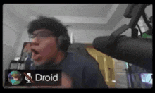a man wearing headphones is talking into a microphone with a sign that says droid in front of him