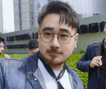 a man with glasses and a beard stands in front of a building that says shanghai
