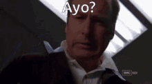 a man looking at a cell phone with the words ayo on the bottom