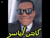 a man in a suit and tie is wearing sunglasses and smiling in arabic
