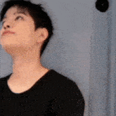 a young man in a black shirt is looking up at something .