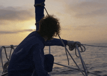 a person sitting on a boat looking out over the ocean