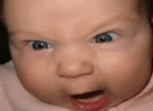 a baby is making a funny face with his mouth open .