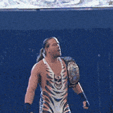 a wrestler wearing a tiger striped outfit is holding a championship belt