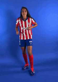 a female soccer player wearing a red and white striped shirt and shorts with the word baku on them