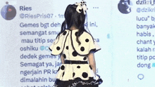 a girl in a polka dot dress is standing in front of a screen that says ries on it