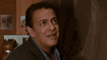 a man in a striped suit is looking out a window and making a surprised face