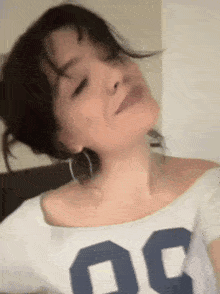 a close up of a woman 's face with her eyes closed wearing a white shirt with the number 30 on it .