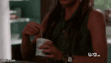 a woman is holding a cup of ice cream and a spoon .