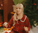 a girl in a plaid shirt is sitting in front of a christmas tree
