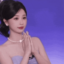 a woman wearing a pearl necklace and a strapless dress is applauding .