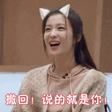a woman with cat ears on her head is smiling with chinese writing behind her