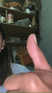 a woman is giving a thumbs up in front of a shelf with a can of condensed milk