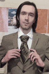 a man in a suit is adjusting his tie in front of a calendar that says 20