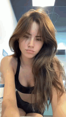 the woman is wearing a black sports bra and shorts and looking at the camera .