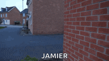 a man in a blue hoodie is standing in front of a brick building and the name jamier is on the bottom