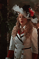 a woman in a white coat and hat stands in front of a palm tree