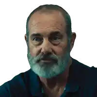 a man with a beard and a blue shirt is looking at the camera