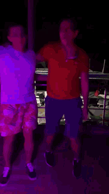 a man in a red shirt is dancing with another man in a white shirt